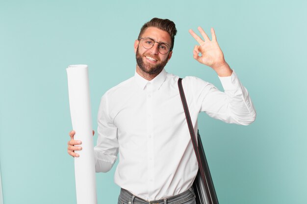 Young handsome man feeling happy, showing approval with okay gesture. architect concept