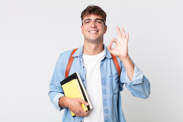 大丈夫なジェスチャーで承認を示して、幸せを感じている若いハンサムな男。大学生のコンセプト