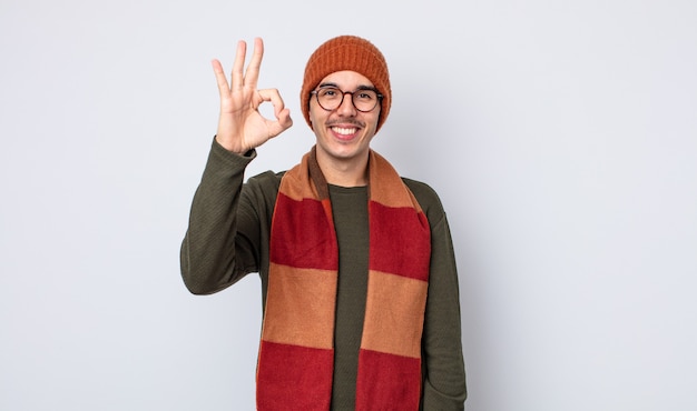 Young handsome man feeling happy, showing approval with okay gesture. winter clothes concept