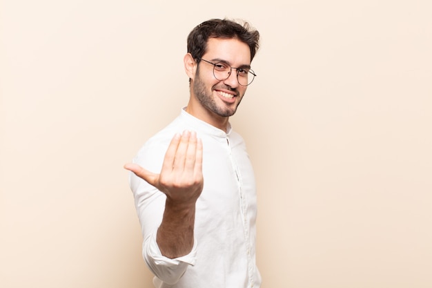 Young handsome man feeling happy, successful and confident, facing a challenge and saying bring it on! or welcoming you