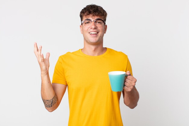 Young handsome man feeling happy, surprised realizing a solution or idea and holding a coffe cup