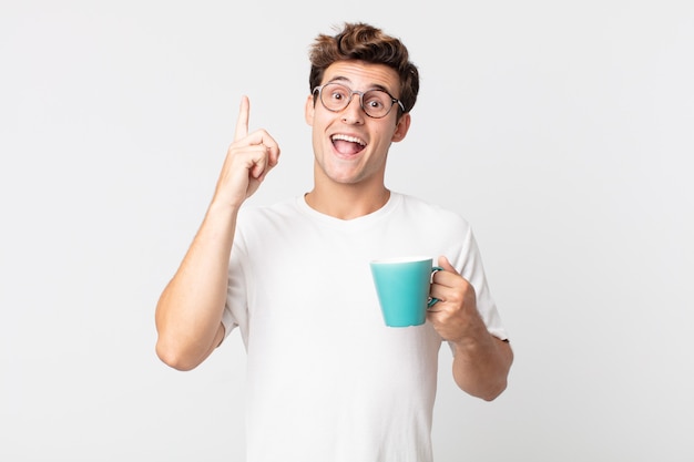 Young handsome man feeling like a happy and excited genius after realizing an idea and holding a coffee cup