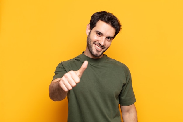 Young handsome man feeling proud, carefree, confident and happy, smiling positively with thumbs up