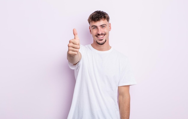 Young handsome man feeling proud, carefree, confident and happy, smiling positively with thumbs up