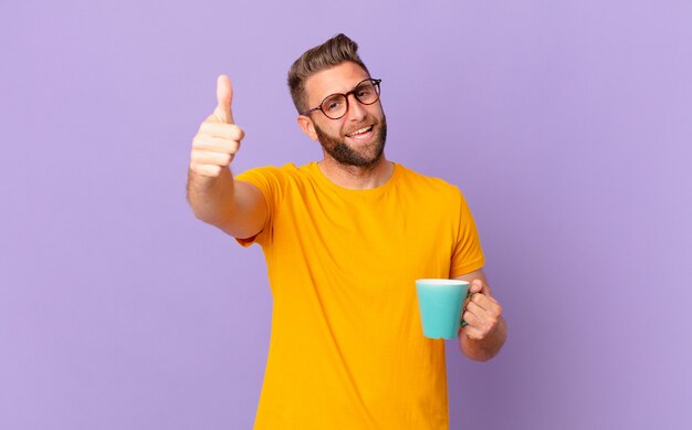 Young handsome man feeling proud,smiling positively with thumbs up. and holding a coffee mug