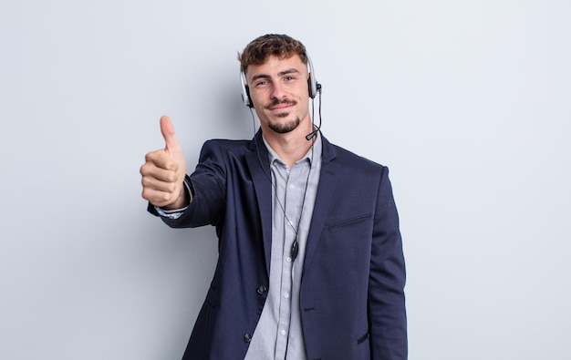 Giovane uomo bello che si sente orgoglioso, sorride positivamente con i pollici in su. concetto di telemarketing