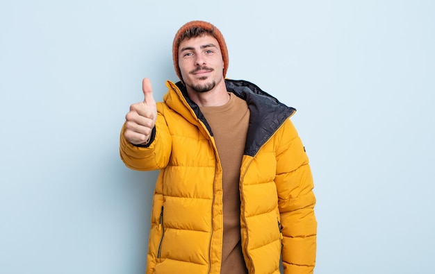 Young handsome man feeling proud,smiling positively with thumbs up. winter concept