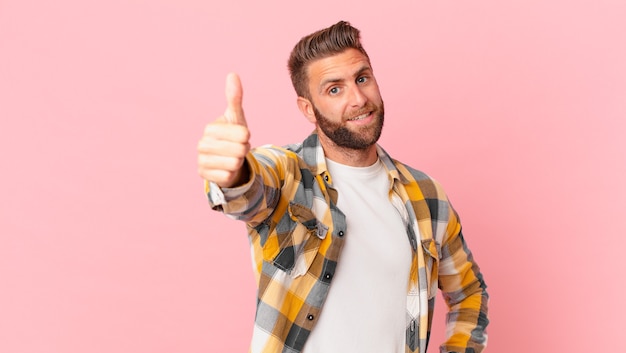 Young handsome man feeling proud,smiling positively with thumbs up