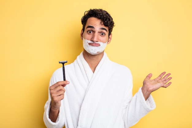 Young handsome man feeling puzzled and confused and doubting. shaving and foam concept