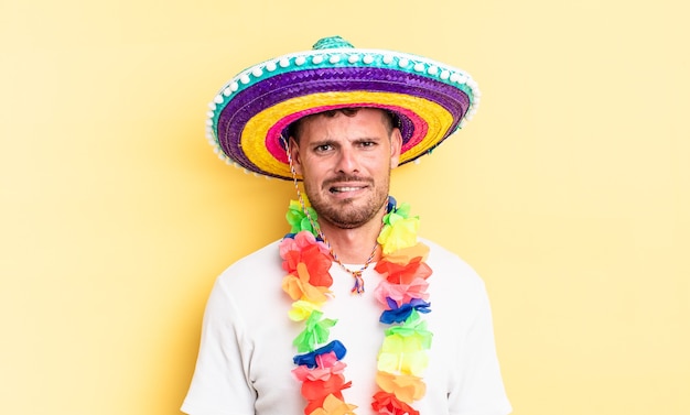 Young handsome man feeling puzzled and confused. mexican party concept