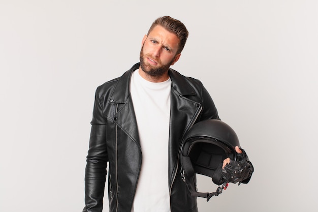 young handsome man feeling puzzled and confused. motorbike helmet concept
