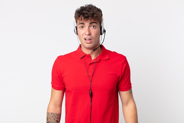 Young handsome man feeling puzzled and confused. telemarketer concept