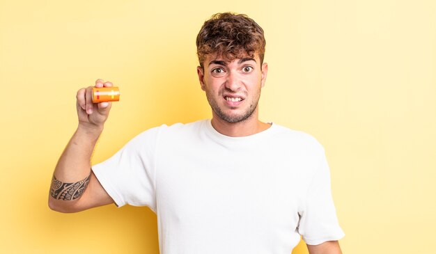 Young handsome man feeling puzzled and confused with a battery