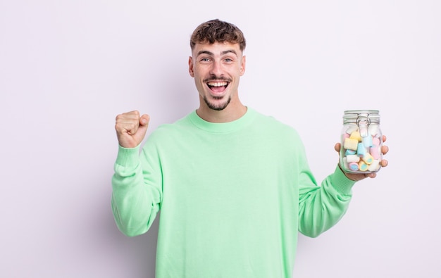 Young handsome man feeling shocked,laughing and celebrating success. jelly candies concept