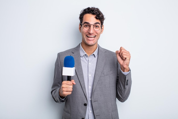 Young handsome man feeling shocked,laughing and celebrating success. presenter with microphone