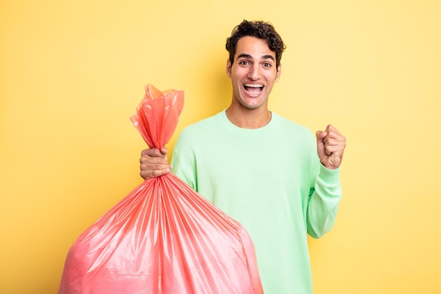 Young handsome man feeling shocked,laughing and celebrating success. trash bag concept