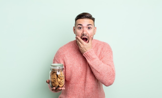 Young handsome man feeling shocked and scared. cookies bottle concept