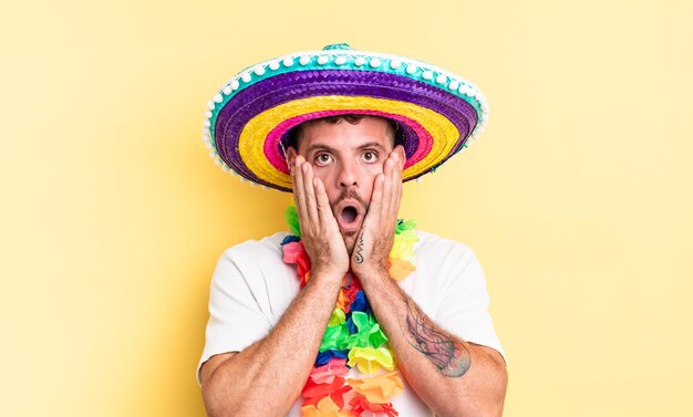 Young handsome man feeling shocked and scared. mexican party concept