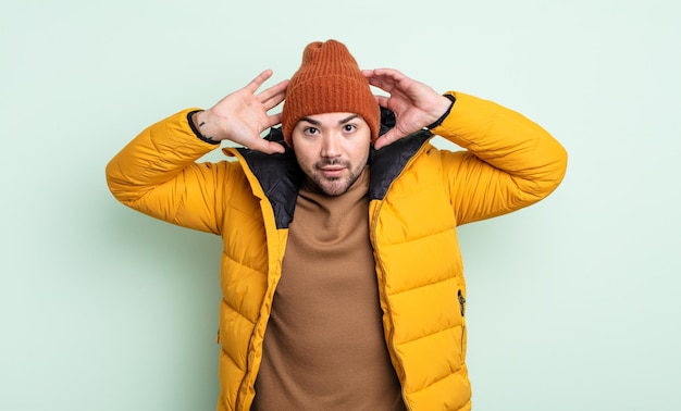 Young handsome man feeling stressed, anxious or scared, with hands on head. cold weather concept