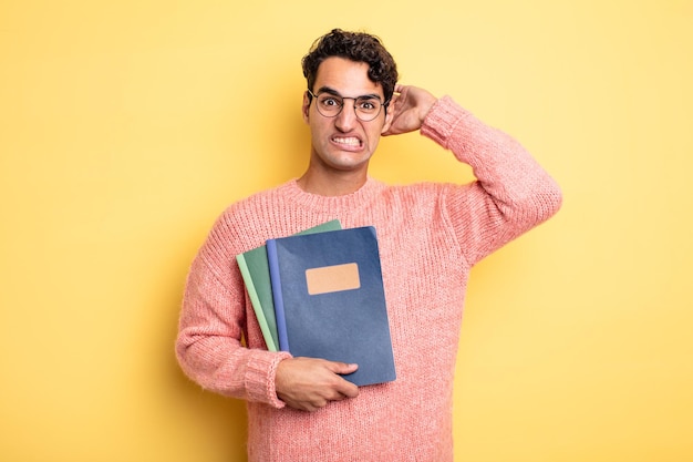 Young handsome man feeling stressed, anxious or scared, with hands on head. notebook concept