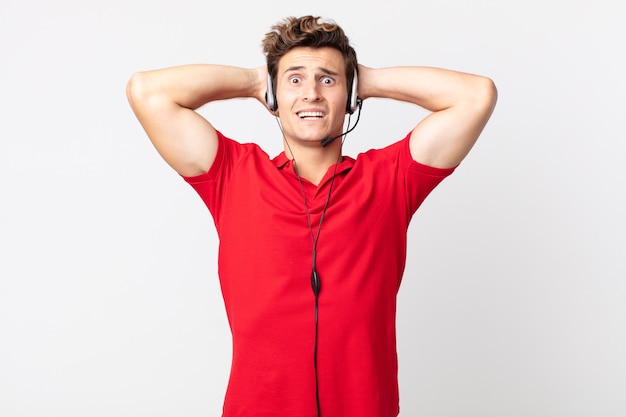 Young handsome man feeling stressed, anxious or scared, with hands on head. telemarketer concept