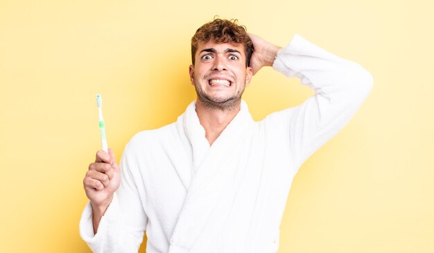 Young handsome man feeling stressed, anxious or scared, with hands on head. toothbrush concept