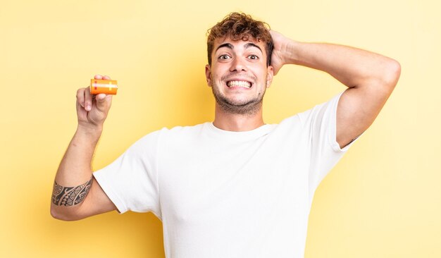 Young handsome man feeling stressed, anxious or scared, with hands on head with a battery