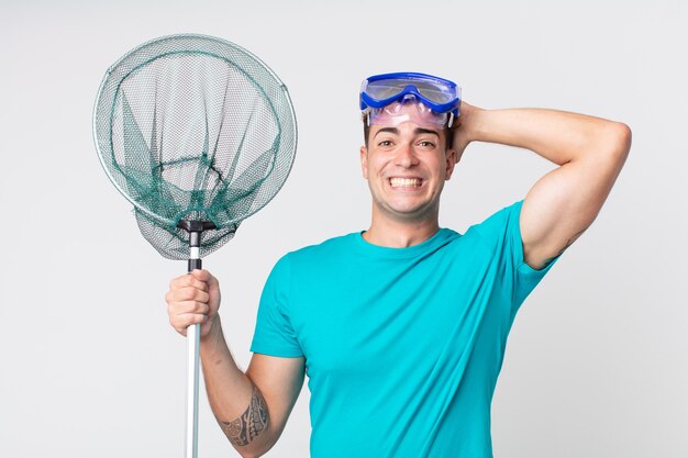 Young handsome man feeling stressed, anxious or scared, with hands on head with goggles and fishing net