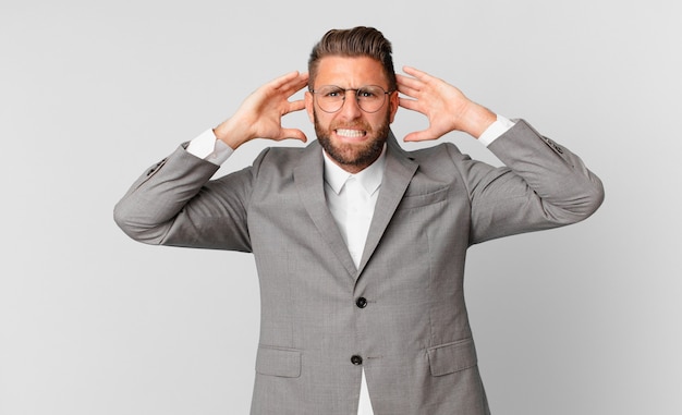 Young handsome man feeling stressed, anxious or scared, with hands on head