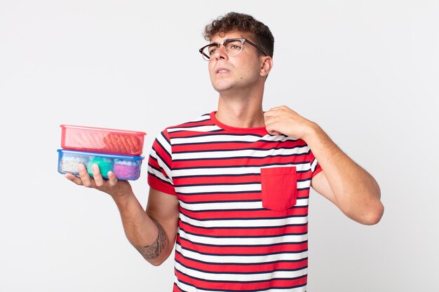 Young handsome man feeling stressed, anxious, tired and frustrated and holding a lunch boxes