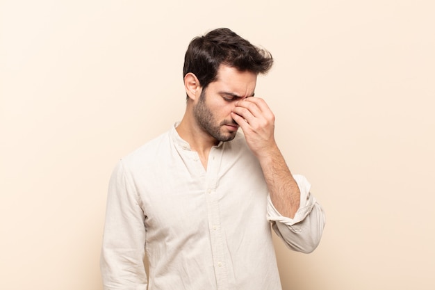 Young handsome man feeling stressed, unhappy and frustrated, touching forehead and suffering migraine of severe headache
