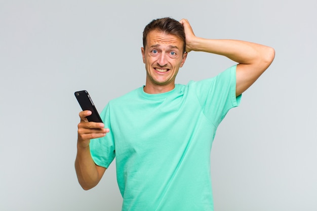 Young handsome man feeling stressed, worried, anxious or scared, with hands on head, panicking at mistake