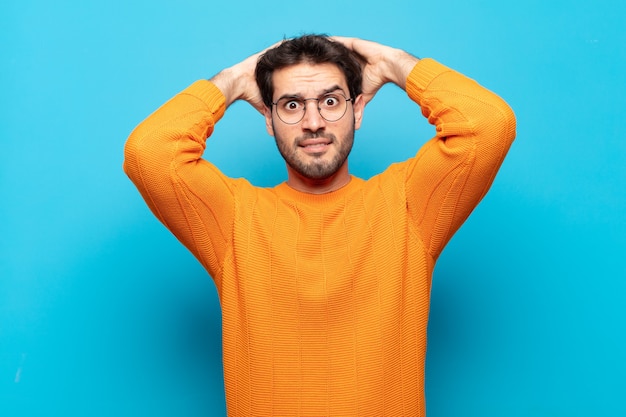 Young handsome man feeling stressed, worried, anxious or scared, with hands on head, panicking at mistake