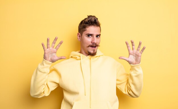 Young handsome man feeling stupefied and scared, fearing something frightening, with hands open up front saying stay away. strange moustache concept