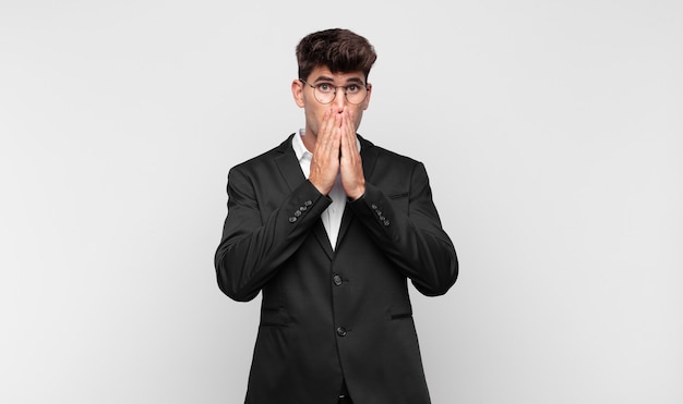 Young handsome man feeling worried, upset and scared, covering mouth with hands, looking anxious and having messed up