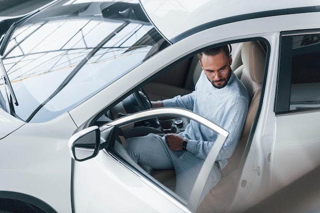 Young handsome man in formal clothes sitting in brand new automobile