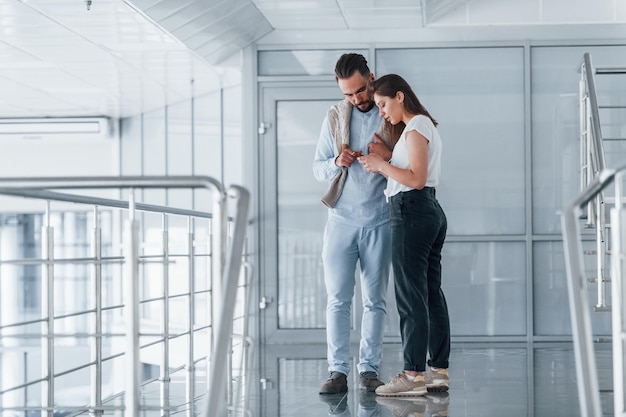 Young handsome man in formal clothes talking with girl indoors in the office at daytime