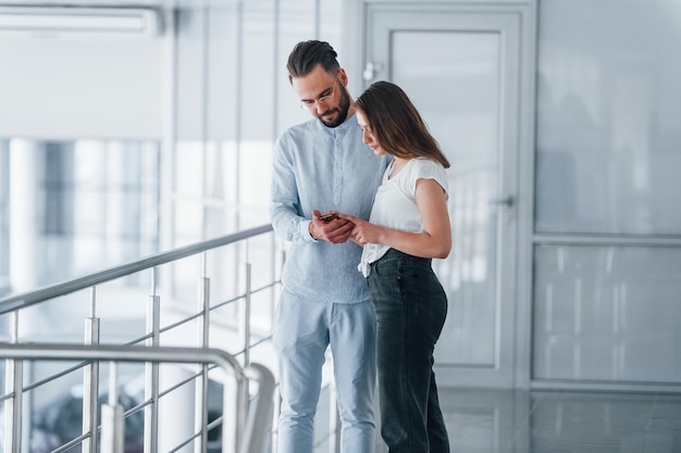 Young handsome man in formal clothes talking with girl indoors in the office at daytime