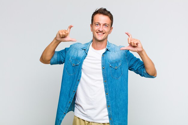 Young handsome man framing or outlining own smile with both hands, looking positive and happy, wellness concept