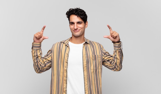 Young handsome man framing or outlining own smile with both hands, looking positive and happy, wellness concept