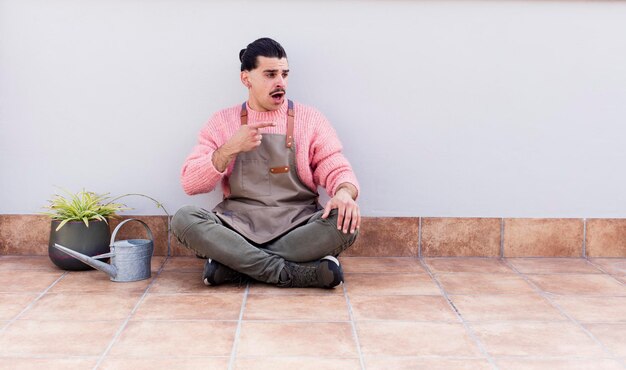 Young handsome man gardering and sitting on the floor outdoors