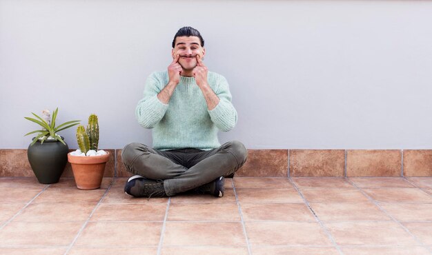 Young handsome man gardering and sitting on the floor outdoors