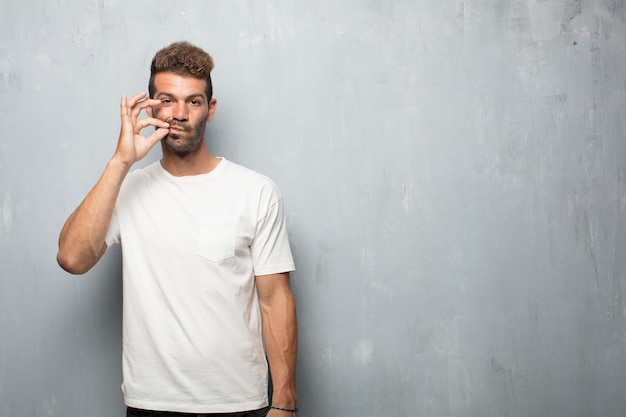 Young handsome man gesturing silence