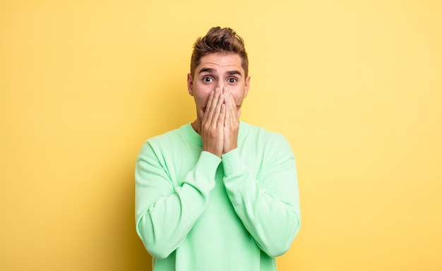 Young handsome man happy and excited, surprised and amazed covering mouth with hands, giggling with a cute expression. strange moustache concept