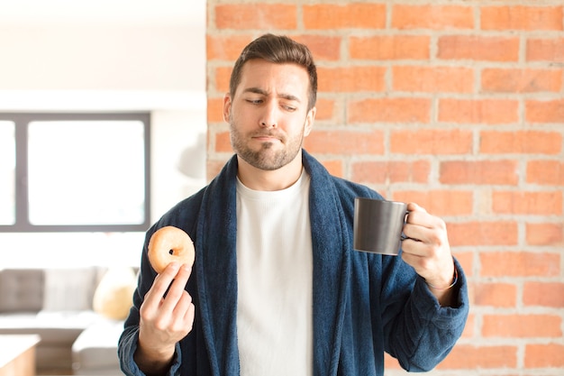 Giovane uomo bello che mangia un caffè a casa