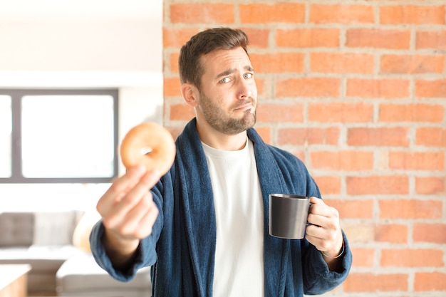 Foto giovane uomo bello che mangia un caffè a casa