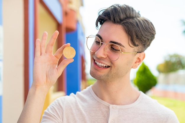 幸せそうな表情でビットコインを保持している若いハンサムな男