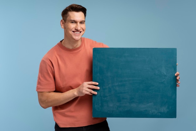 Photo young handsome man holding blank empty banner looking positive