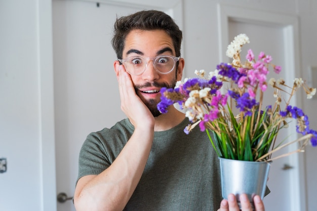 自宅で花を持って若いハンサムな男