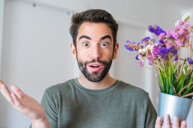 自宅で花を持って若いハンサムな男